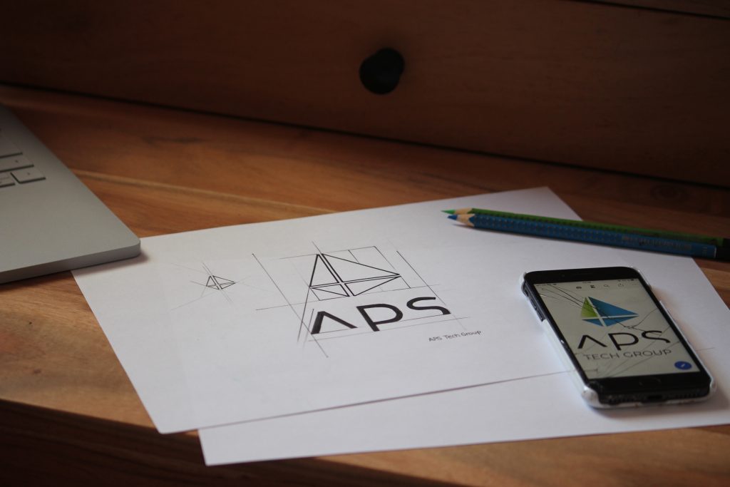 Eine Zeichnung und die Smartphone Ansicht APS Tech Group Logos